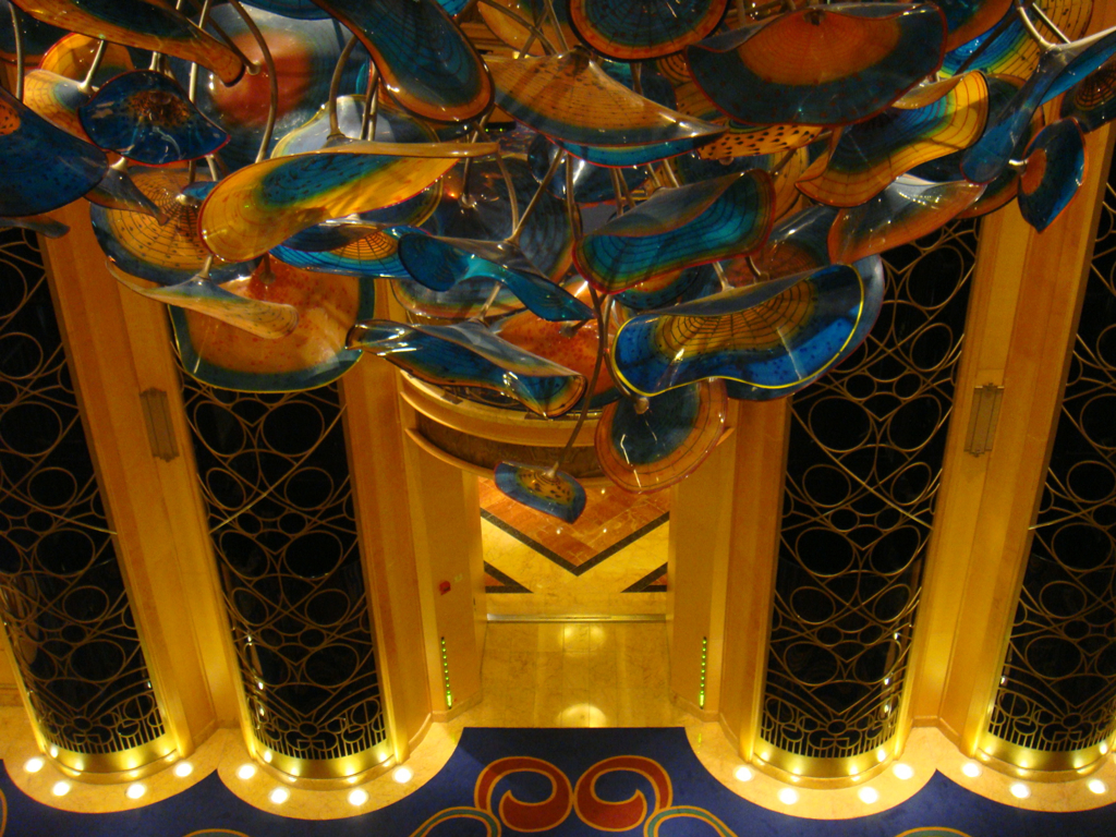 Close view looking down through Disney Wonder's colorful atrium chandelier toward the elevator area